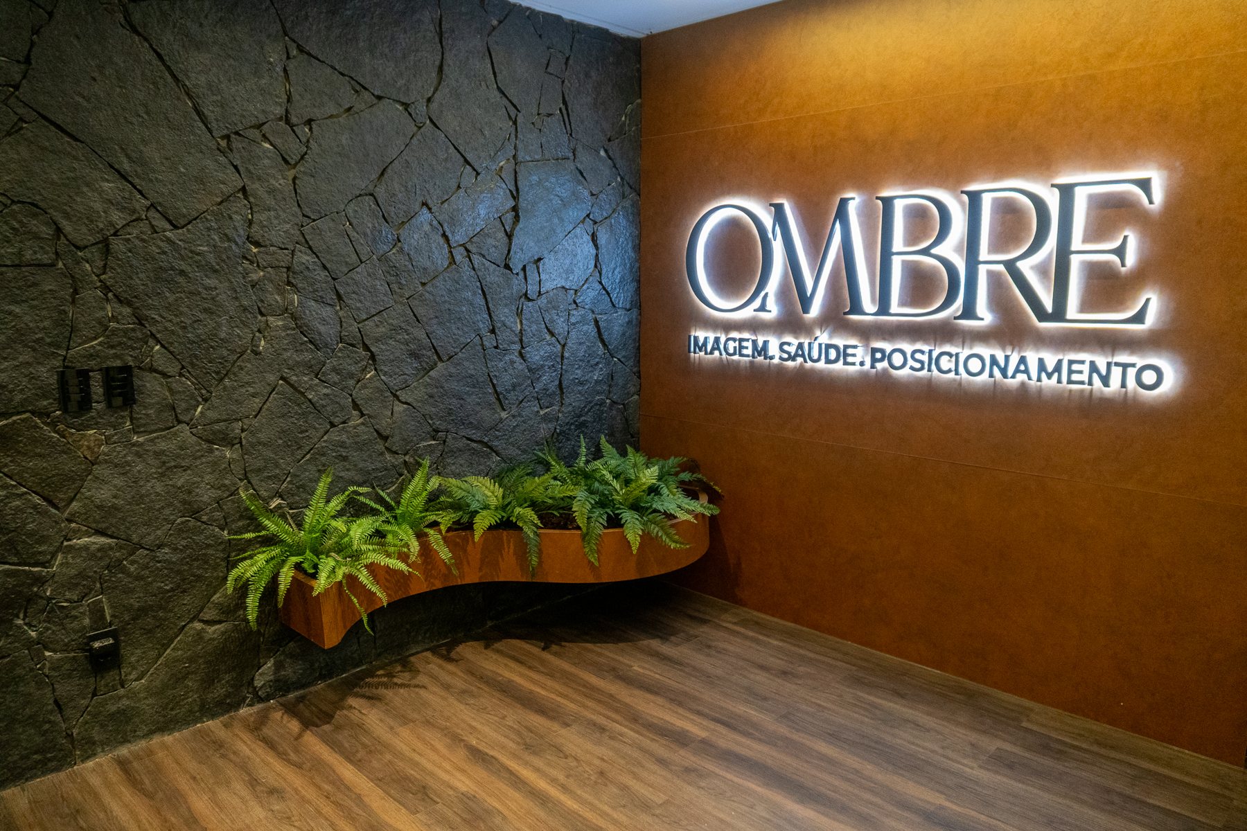 Parede iluminada com o logo OMBRE